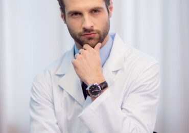 Młody lekarz trzyma się zastanawiająco za brodę