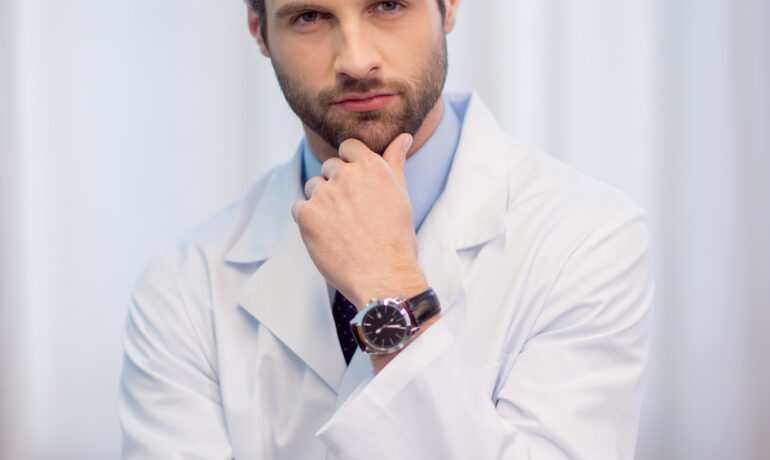 Młody lekarz trzyma się zastanawiająco za brodę