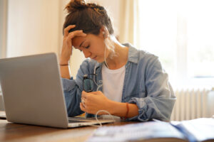 Młoda kobieta odczuwa stres siedząc przed laptopem