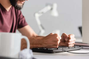 Mężczyzna siedzi z zaciśniętymi pięściami przy komputerze